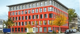 In diesem modernen Gebäude mit roter Außenfassade befindet sich der Sitz des QM Vereins.